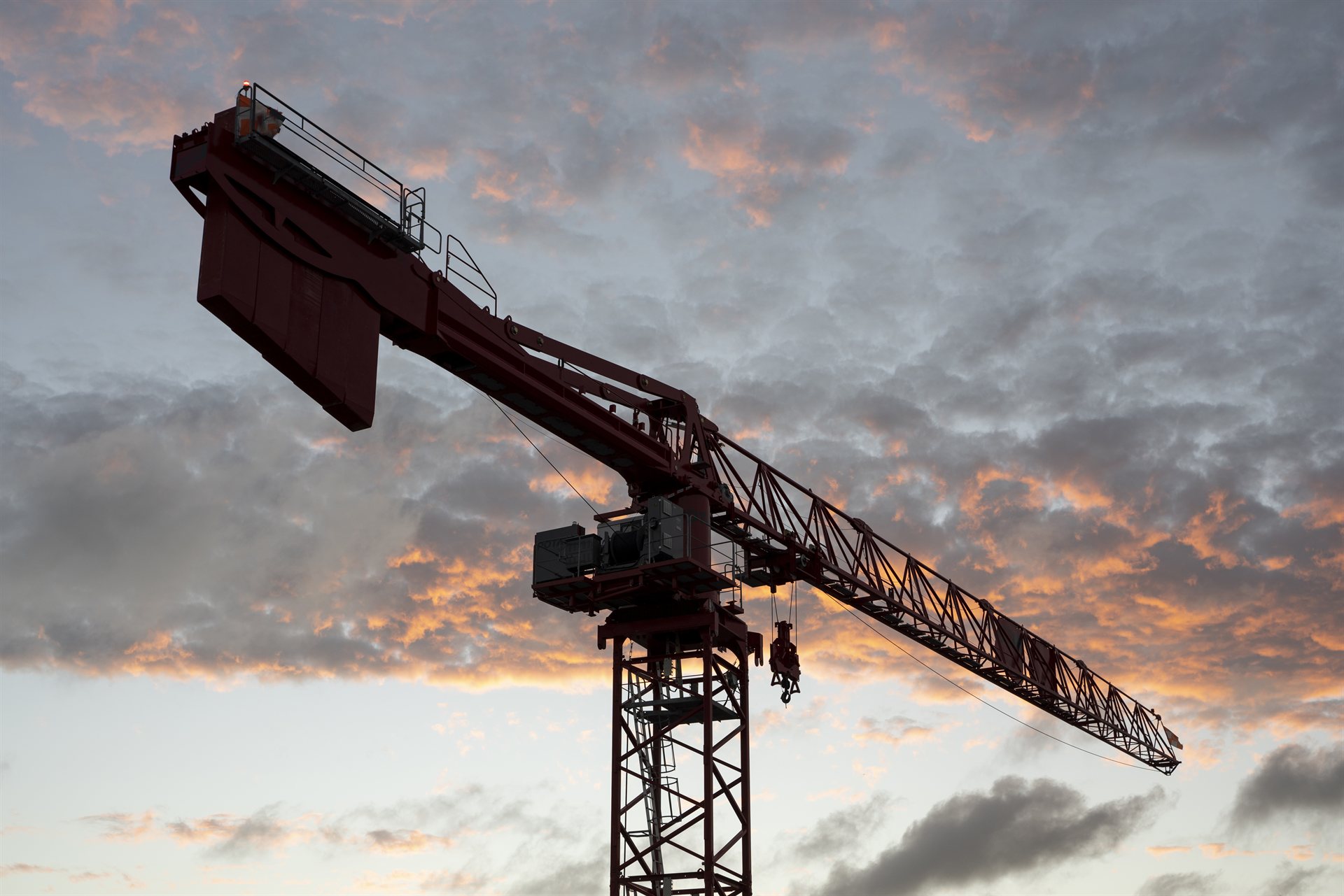 Tower crane silhouetted against a sunset sky on a construction site